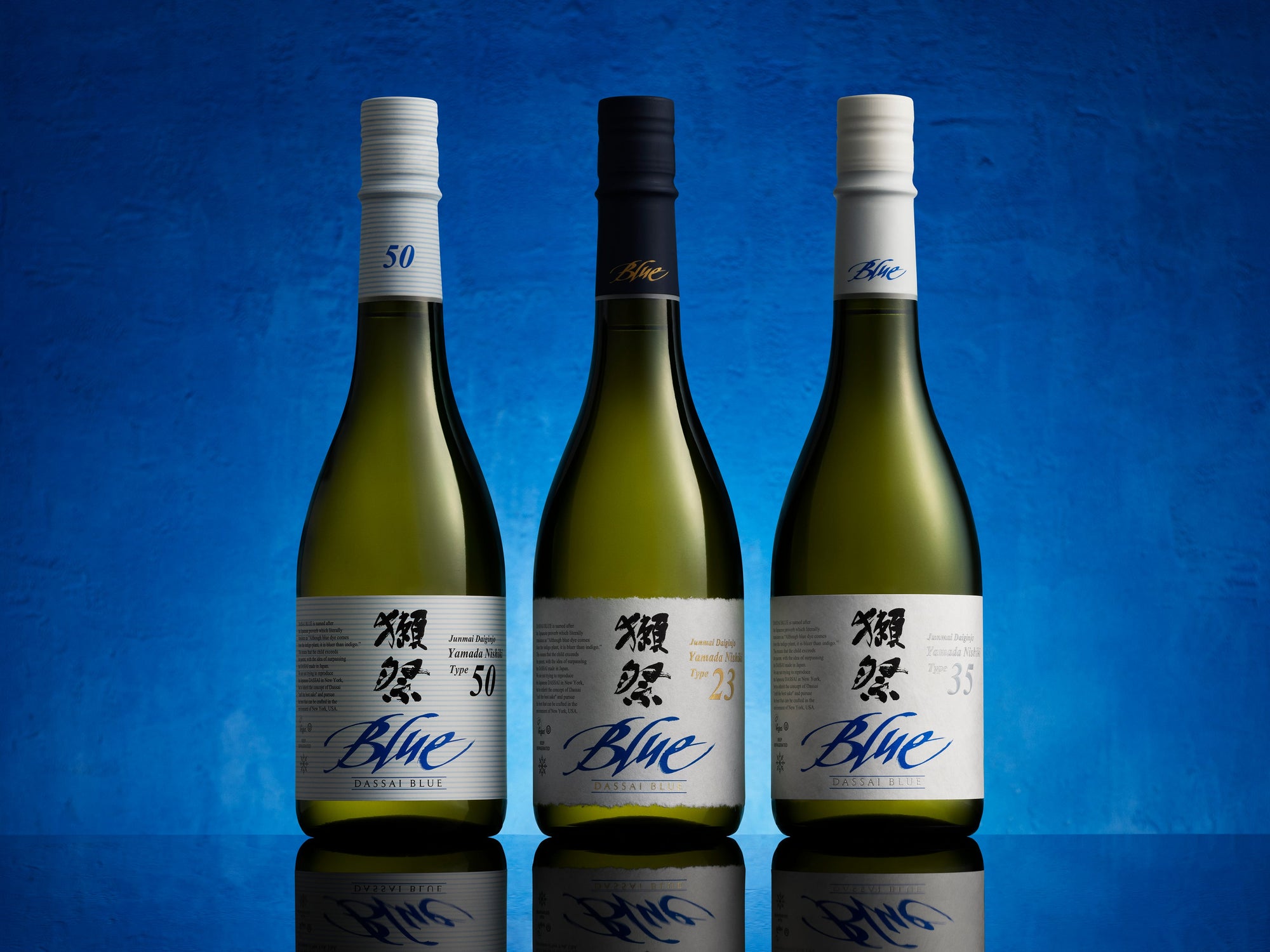 Three bottles of Dassai Blue brand sake on a blue background